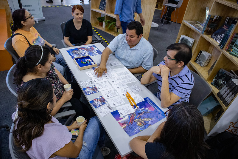Mesa de juego en la Feria del Libro de Monterrey, Un miembro de la comunidad Leyendas del Noreste explica a los asistentes en qué consiste una partida del juego Secretaría de Asuntos Paranormales.