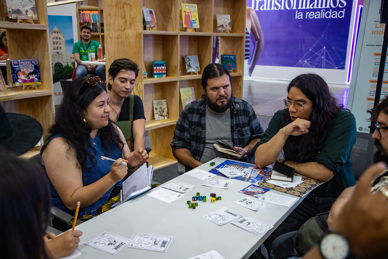 Mesa de juego en la Feria del Libro de Monterrey, Un miembro de la comunidad Leyendas del Noreste explica a los asistentes en qué consiste una partida del juego Secretaría de Asuntos Paranormales.