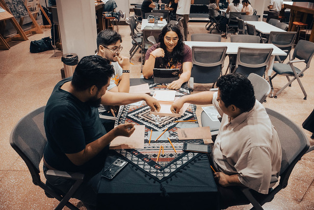 Mesa con cuatro personas sentadas alrededor mientras juegan una partida de rol.