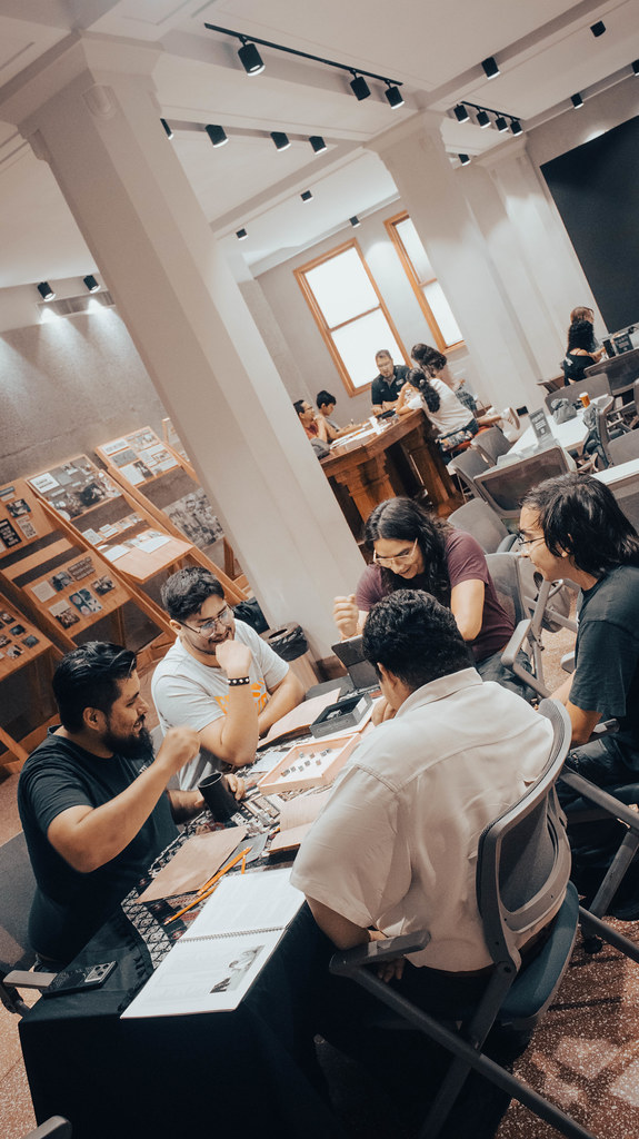 Mesa con cuatro personas sentadas alrededor mientras juegan una partida de rol.